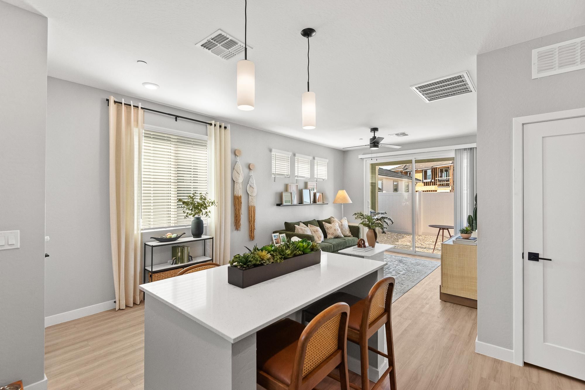 Verge Apache Junction modern living room with green sofa, wall art, large rug, and sliding glass doors opening to a sunny patio.