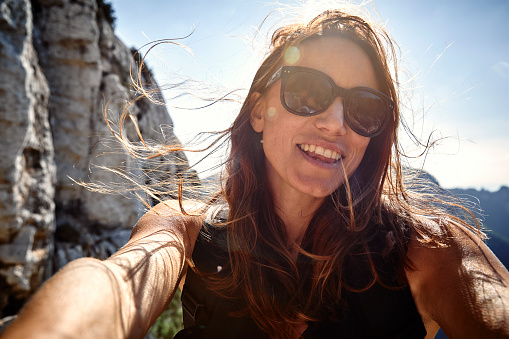 A young beautiful woman on a Summer hike in nature in Ibiza with cliffs and the sea in the background.