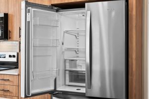 Open stainless steel refrigerator with empty shelves and drawers in a modern kitchen setting.